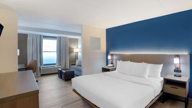 Habitación de hotel con una cama grande, un escritorio, una silla y vista al mar por la ventana.
