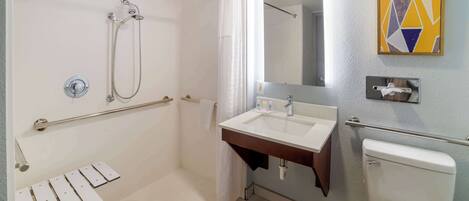 A modern bathroom with a shower, toilet, sink, and a mirror.