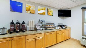 Una cocina con dispensadores de café, un microondas y un televisor en la pared.