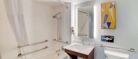 A modern bathroom with a bathtub, shower, sink, and toilet.