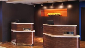 A reception area with two wooden reception desks, each with a digital screen and a small window. - Courtyard by Marriott Cleveland Westlake (Westlake)
