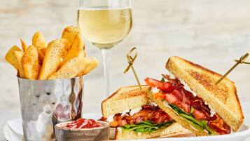 A sandwich with a side of fries and a glass of white wine.
