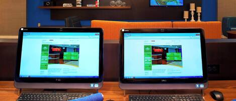 Two desktop computers on a wooden desk with a keyboard and mouse in front of each.