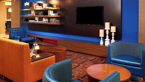A modern lounge area with seating, a flat-screen TV, and decorative items on shelves. - Courtyard by Marriott Cleveland Westlake (Westlake)
