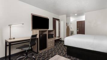 Habitación de hotel con cama, escritorio, silla, televisión y armario.