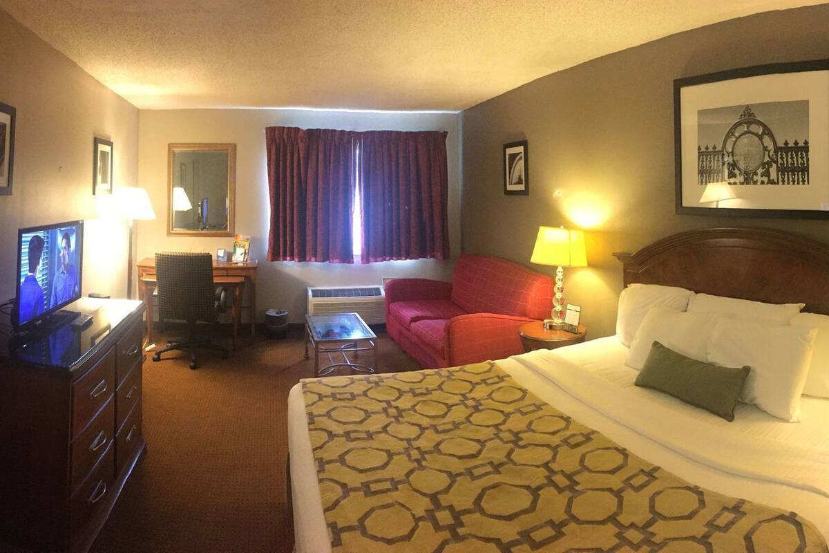 Habitación de hotel con cama, escritorio, silla y televisión.