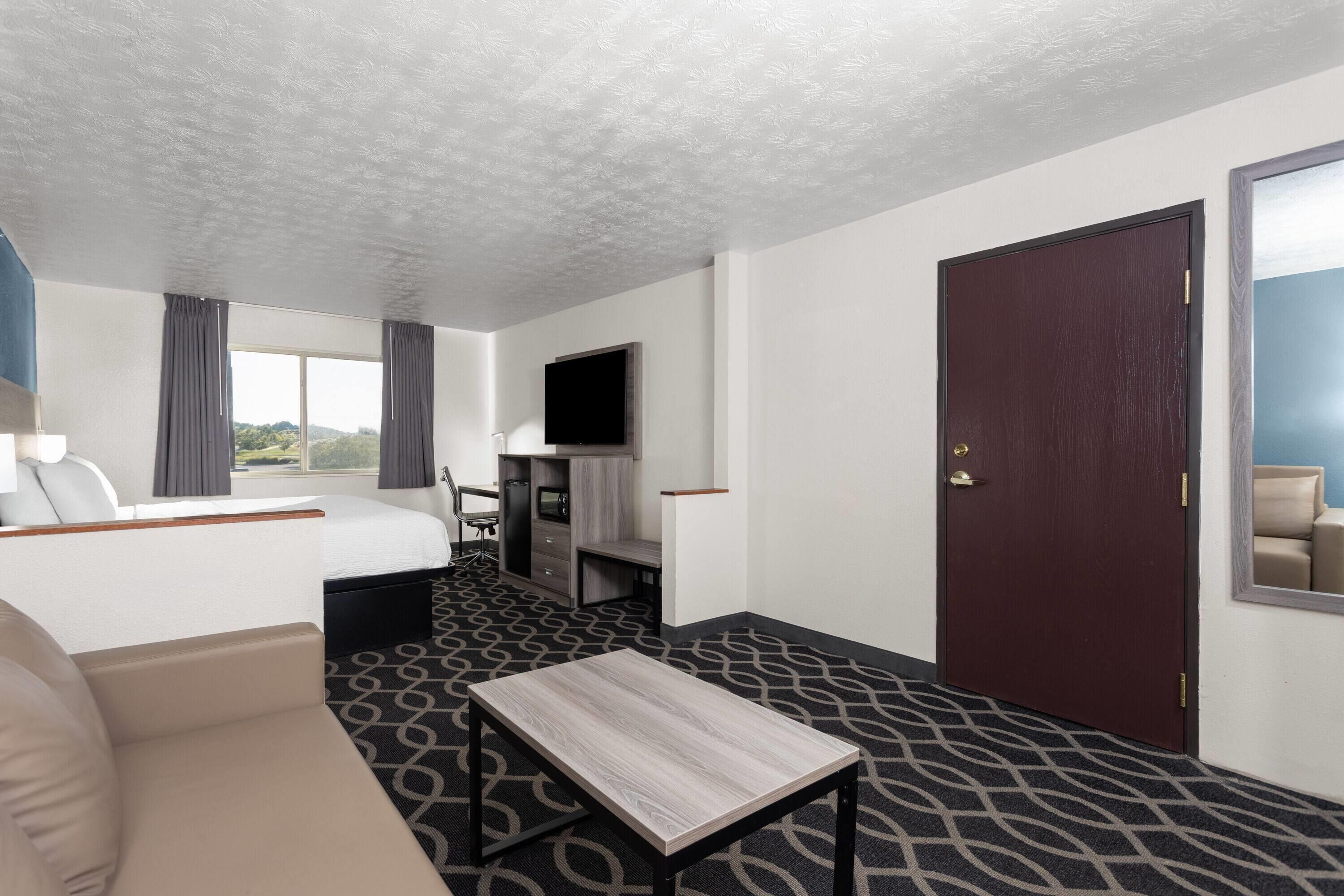 Habitación de hotel con cama, televisión, escritorio y vistas al exterior.