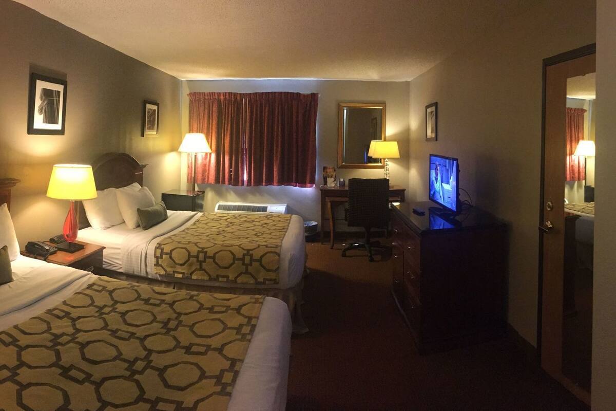 Habitación de hotel con dos camas, un escritorio, un televisor y un espejo.