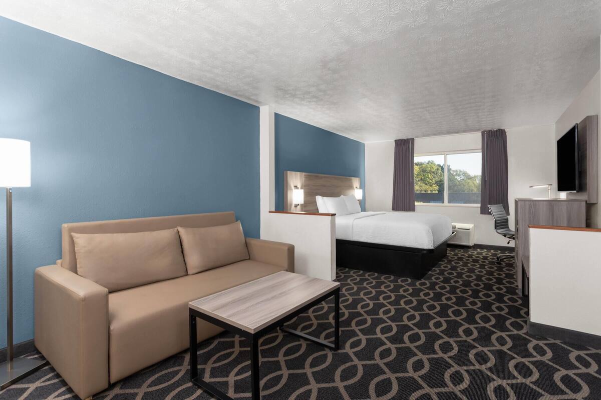 Una habitación de hotel con cama, sofá, escritorio y televisor.