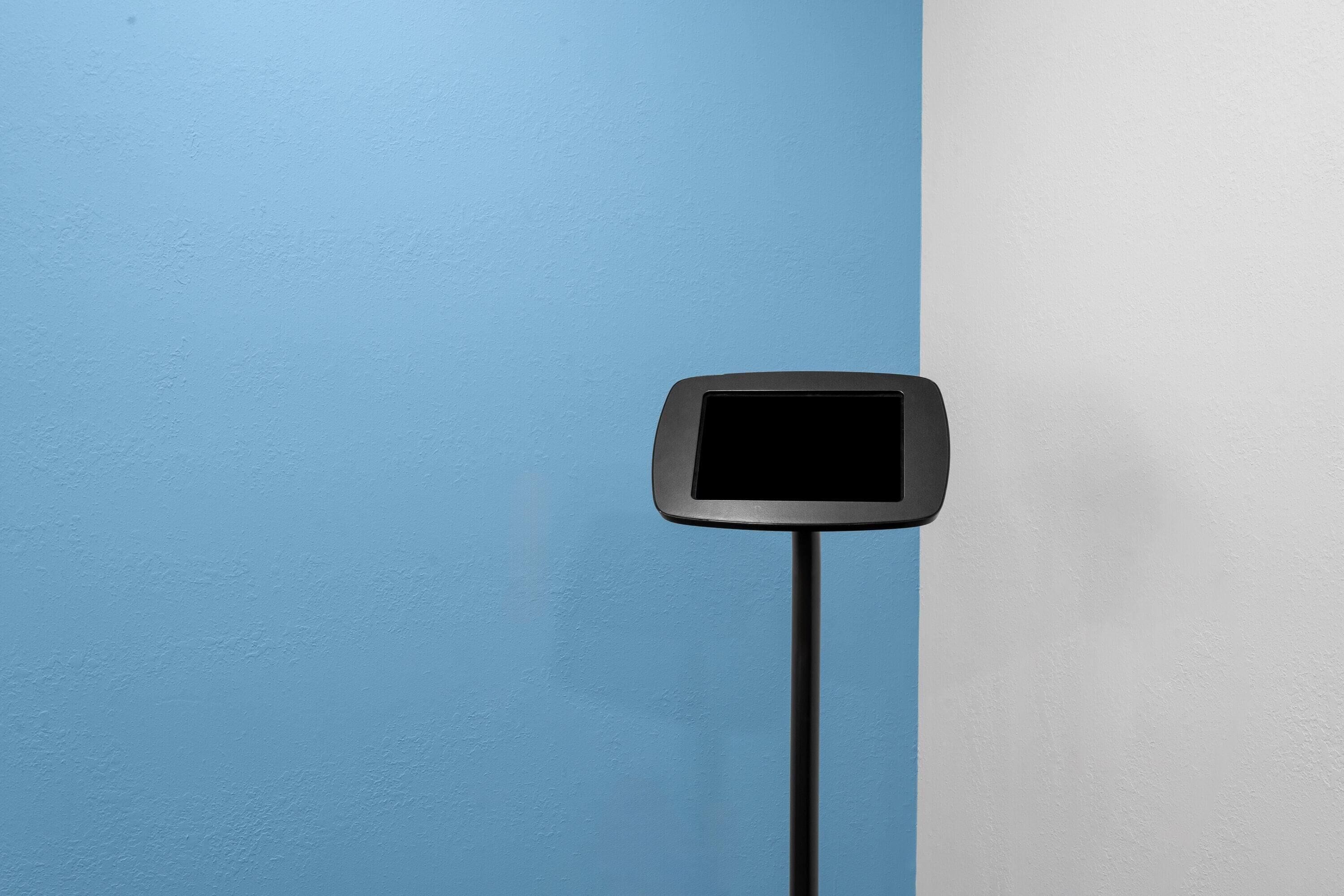 A black digital display mounted on a pole against a blue and white wall.
