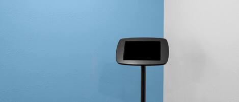 A black digital display mounted on a pole against a blue and white wall.