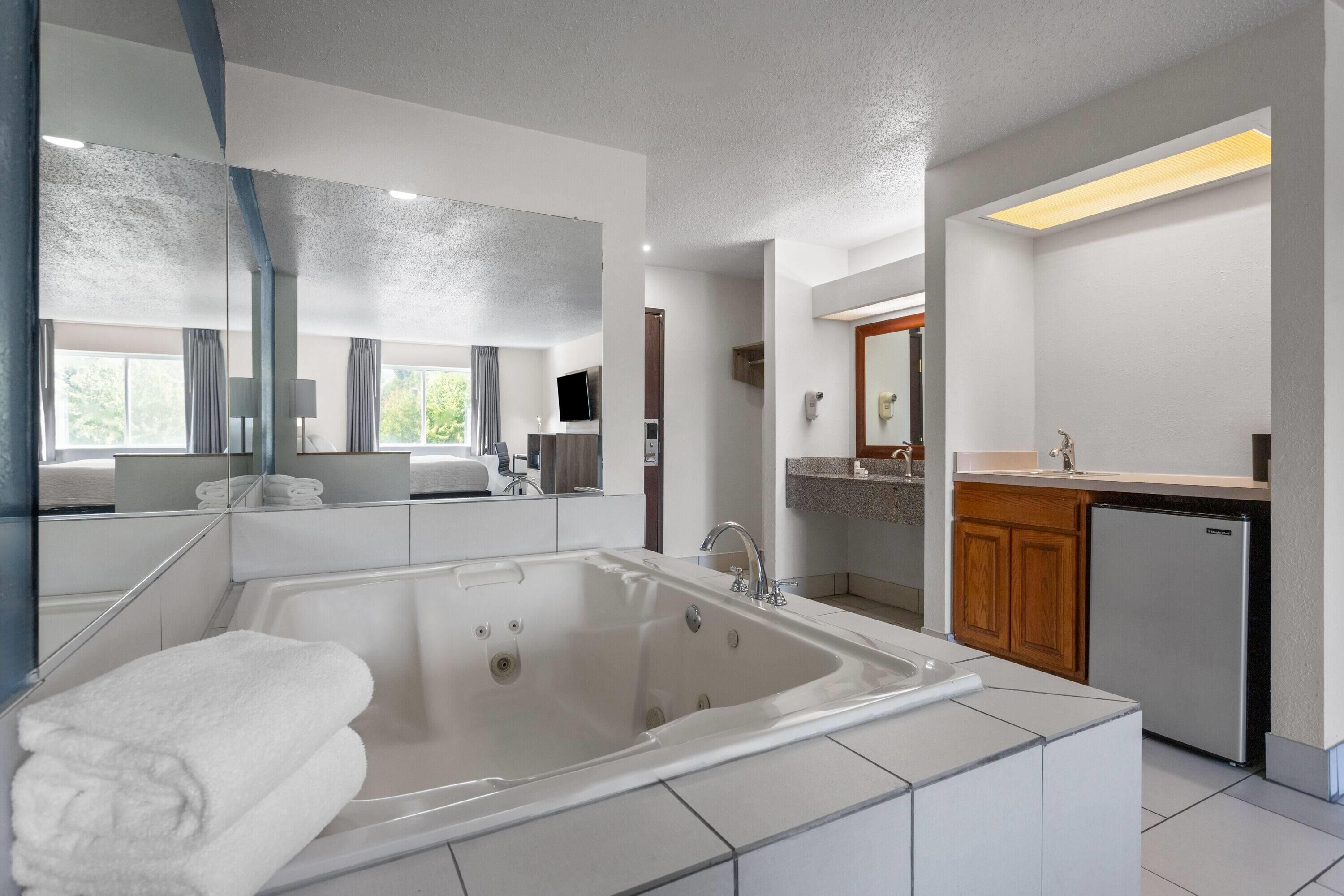 Une salle de bain moderne avec une grande baignoire, un lavabo et un miroir.