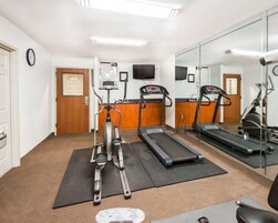 Un gimnasio con cintas de correr, elíptica y bicicleta estática.