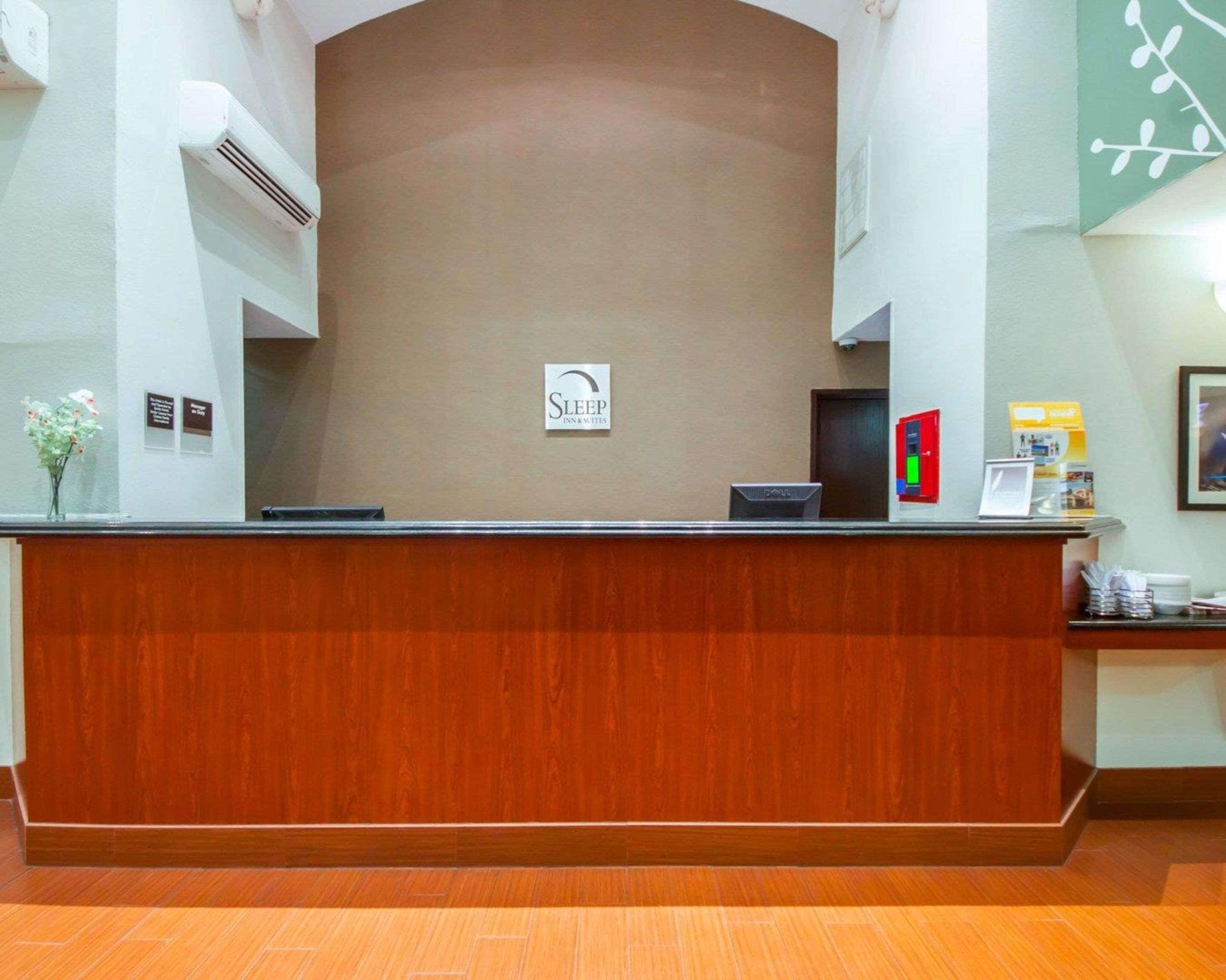 Un mostrador de recepción con un letrero que dice "Sleep Inn & Suites", una computadora Dell y una caja de alarma contra incendios.