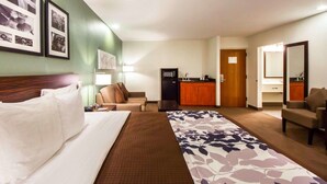 Ein Hotelzimmer mit Bett, Schreibtisch, Stuhl, einer Küchenzeile und einem Badezimmer.