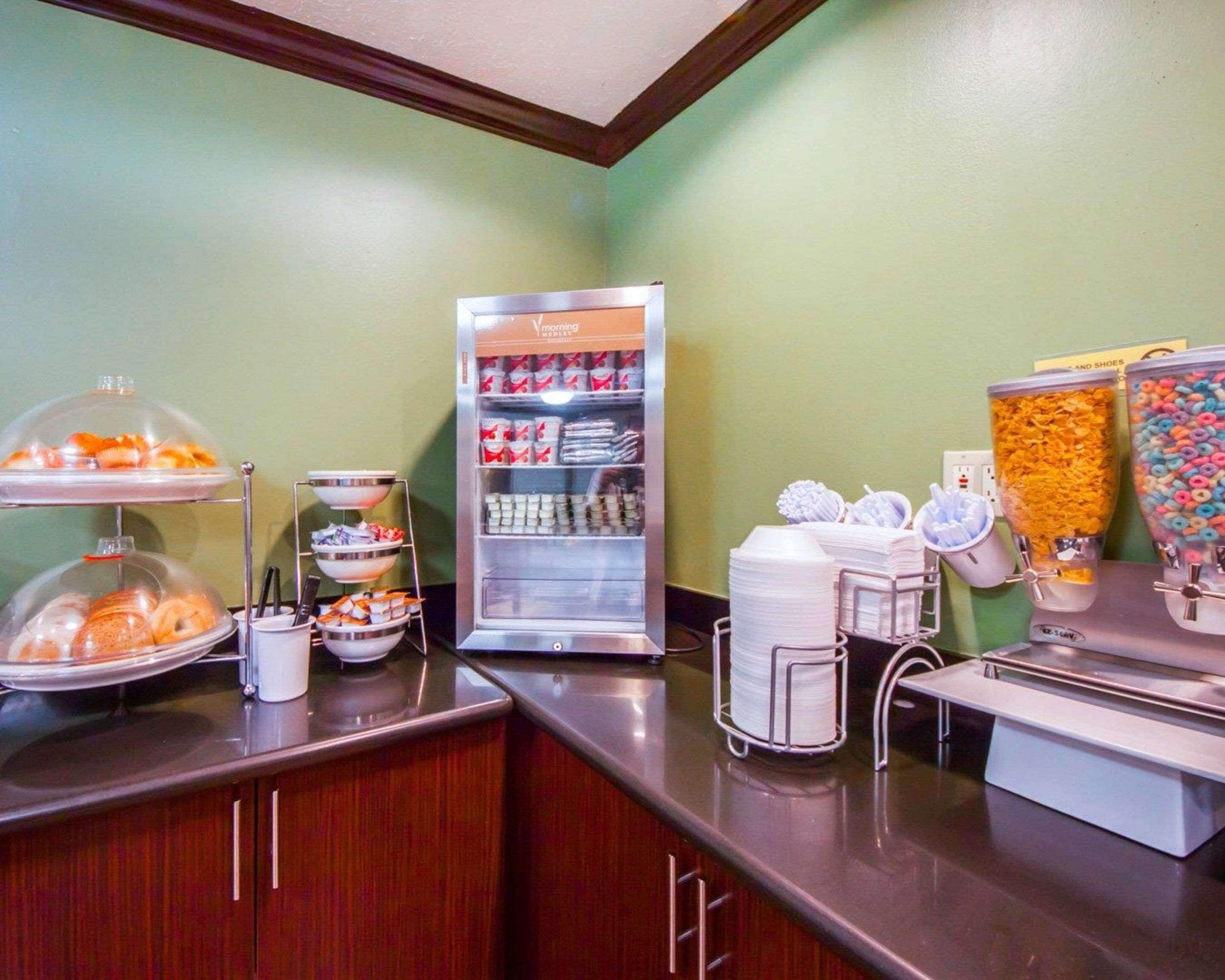 A breakfast bar with a variety of food items, including pastries, beverages, and cereal.