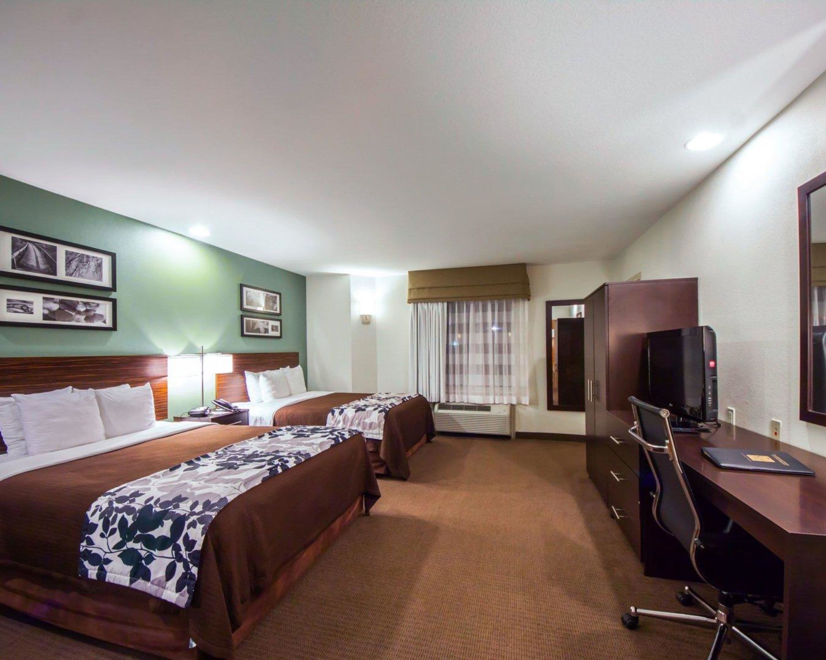 Ein Hotelzimmer mit zwei Betten, einem Schreibtisch, einem Stuhl, einem Fernseher und einem Kleiderschrank.