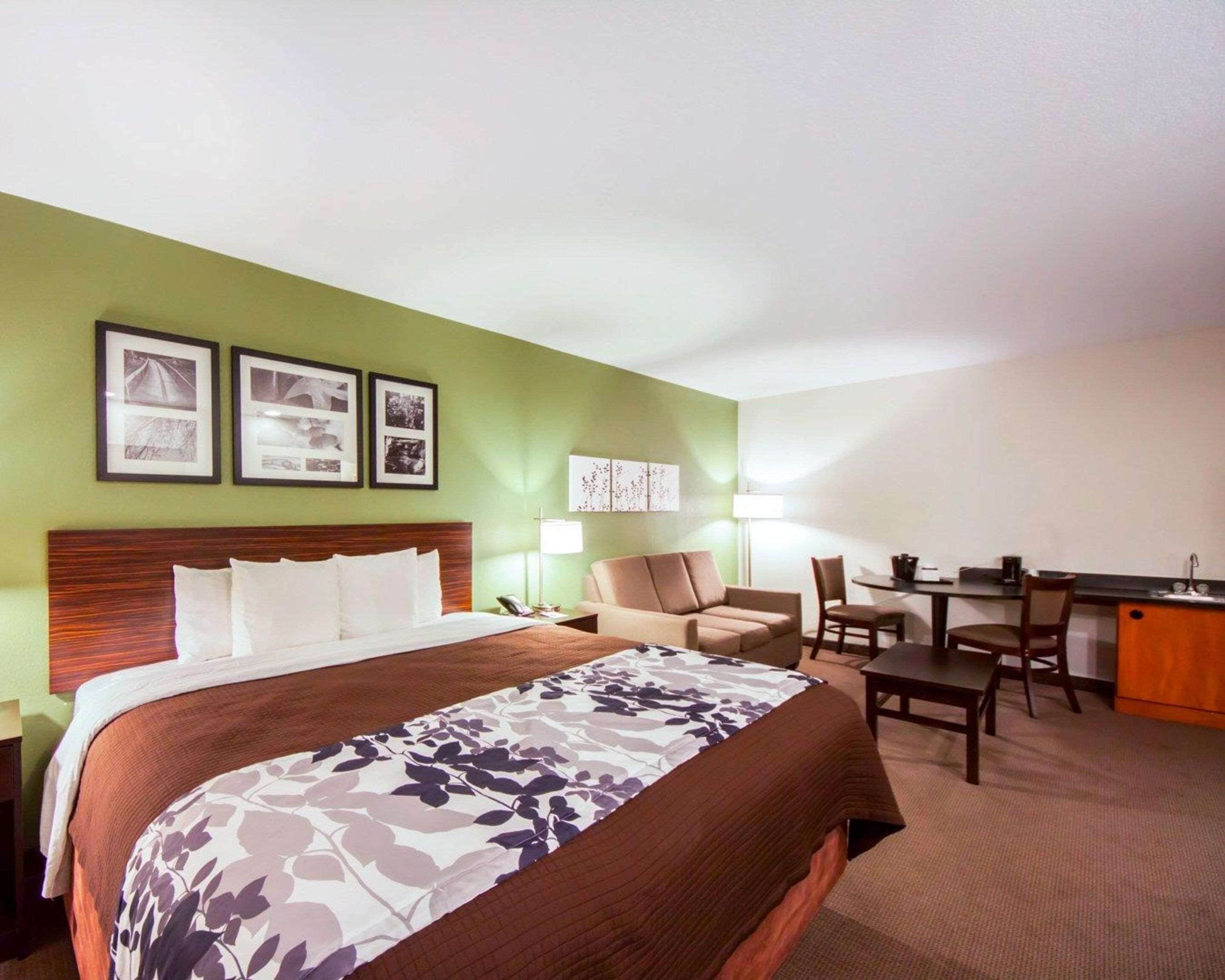 Ein Hotelzimmer mit einem großen Bett, einem Schreibtisch, einem Sessel und einer Couch. An der Wand hängen gerahmte Bilder.