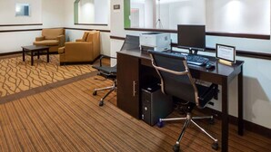 Ein Hotelzimmer mit Schreibtisch, zwei Stühlen, einem Computer und einem Drucker.