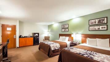Habitación de hotel con dos camas, un escritorio con ordenador, una silla y una pequeña cocina.
