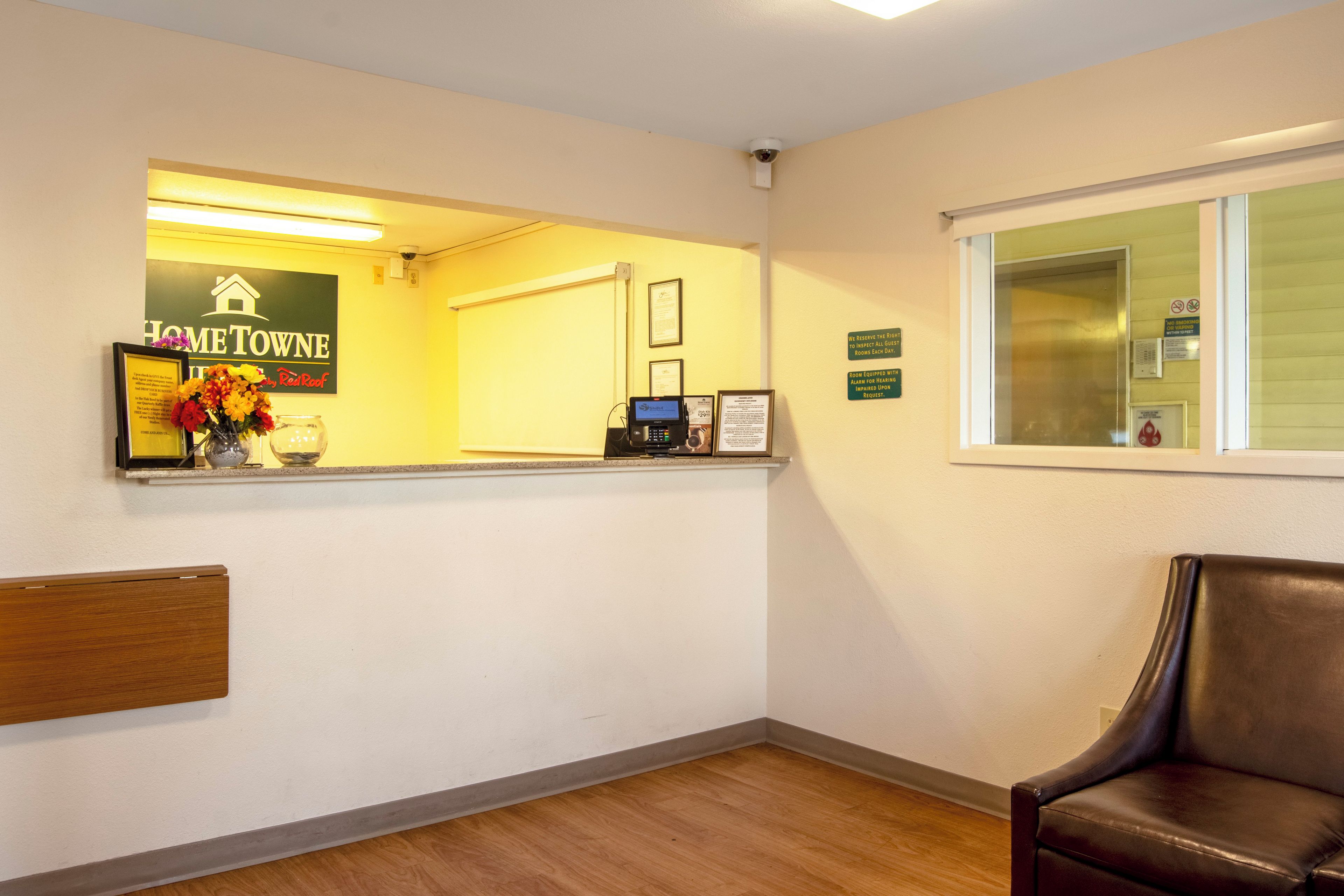 A reception area with a reception desk, a framed welcome sign, a window with a view, and a leather chair.