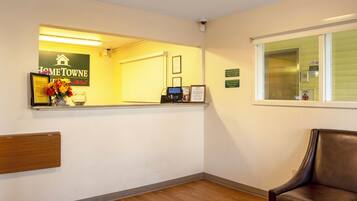 A reception area with a reception desk, a framed welcome sign, a window with a view, and a leather chair.