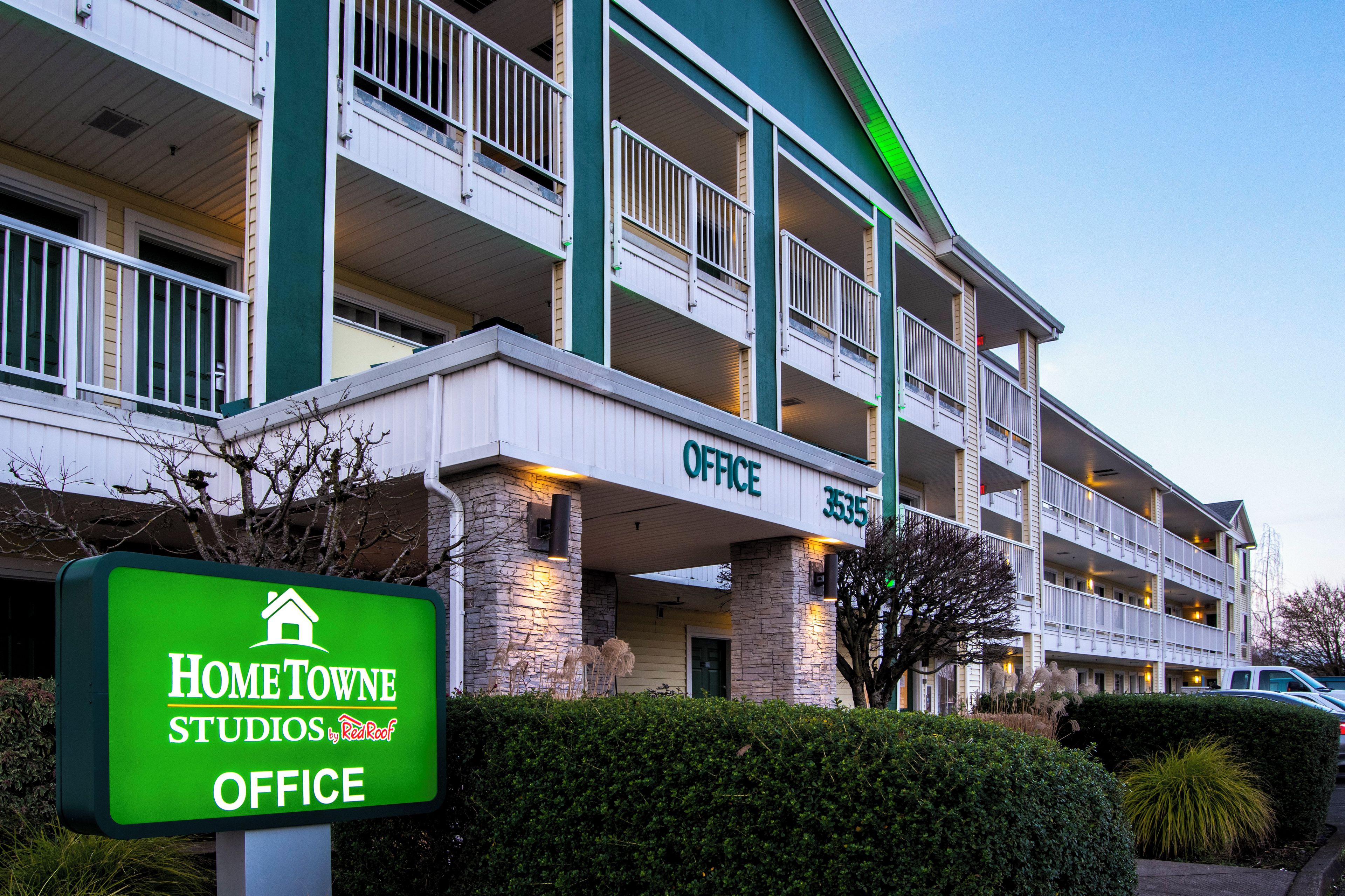 A multi-story hotel with a sign indicating 'Home Towne Studios by Red Roof Office.'