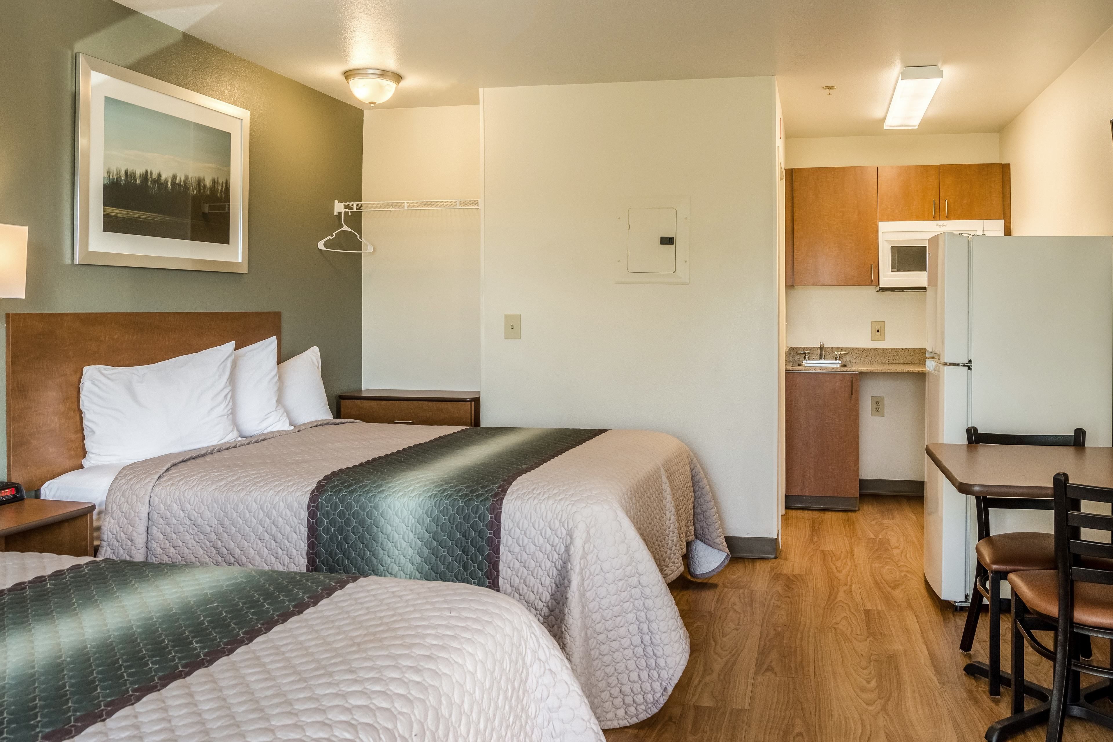 Una habitación de hotel con dos camas, una kitchenette y una zona de comedor.