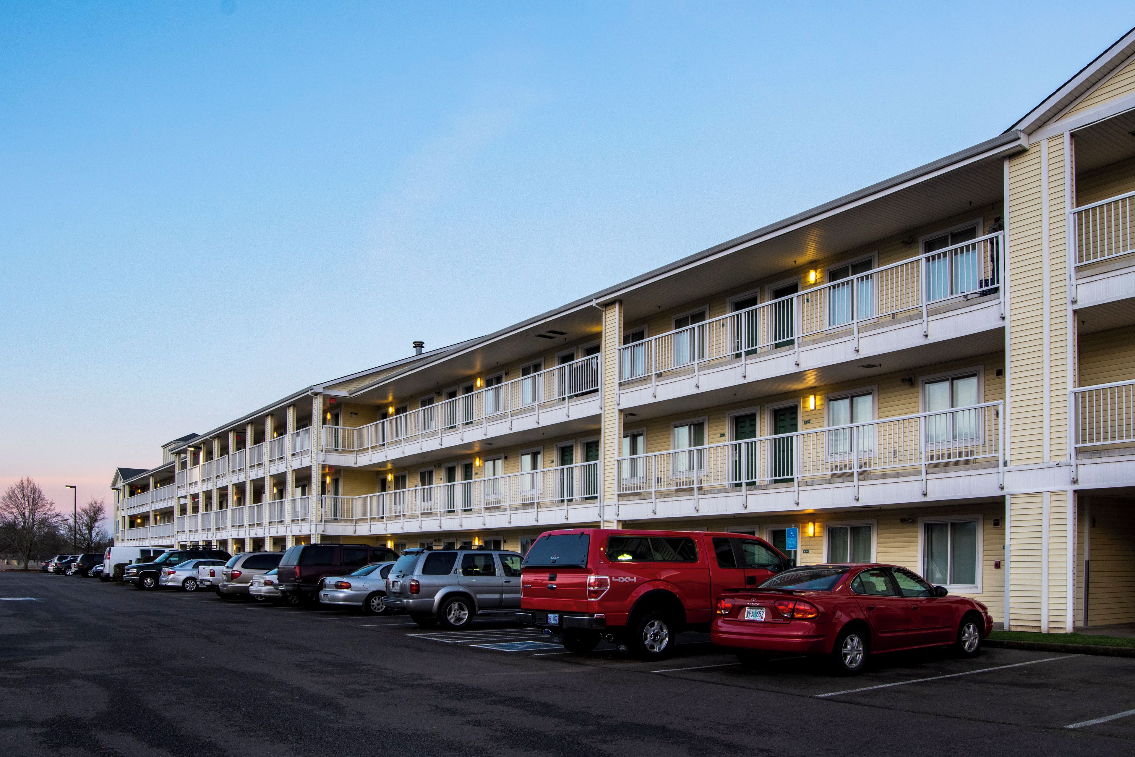 A multi-story motel with a row of parking spaces in front.
