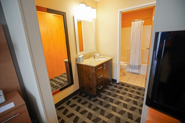 Une salle de bain d’hôtel avec un meuble-lavabo en bois, un grand miroir, un lavabo et un espace douche.