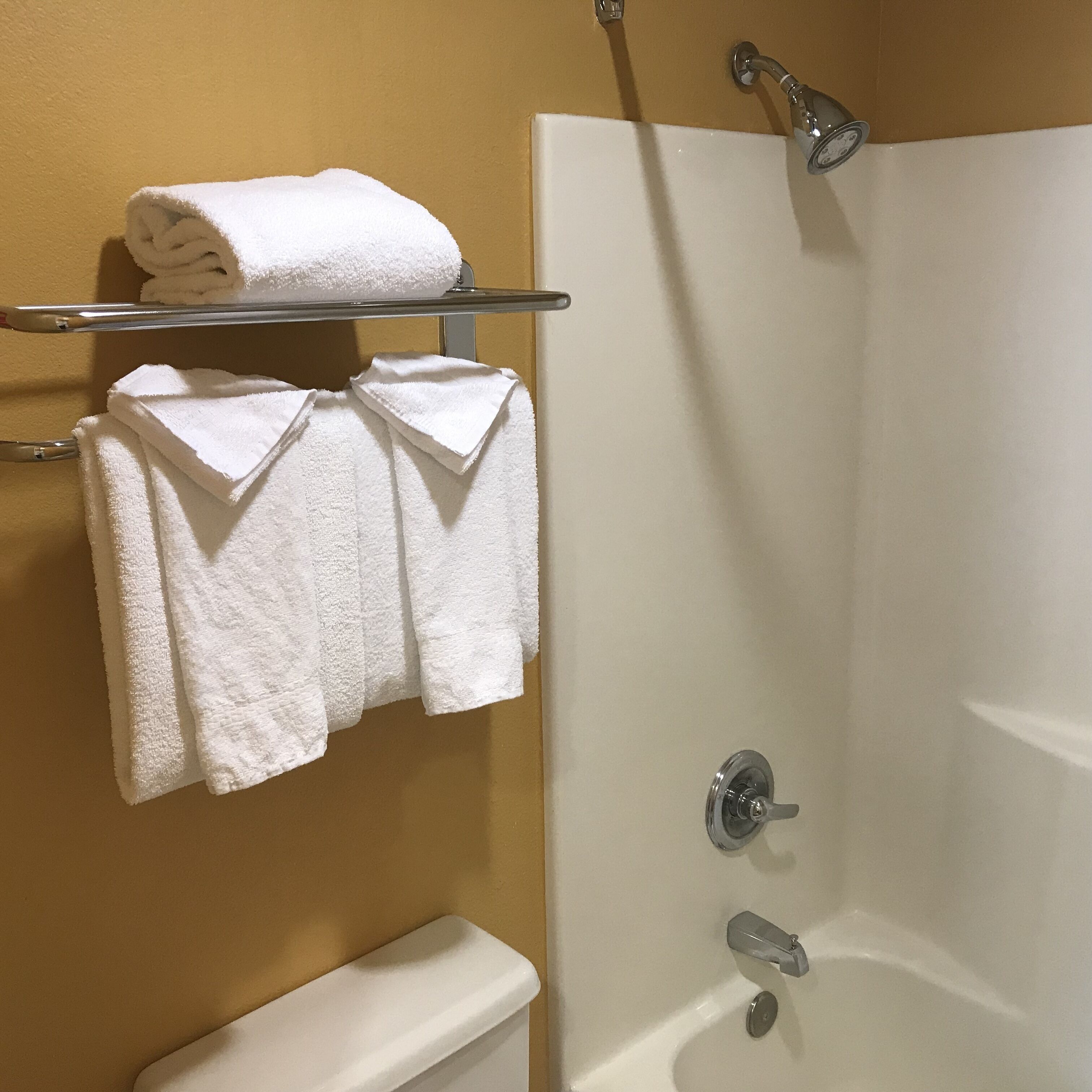 Une salle de bain avec une baignoire blanche, des toilettes et un porte-serviettes avec des serviettes pliées.