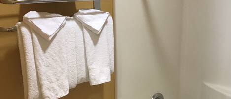 Une salle de bain avec une baignoire blanche, des toilettes et un porte-serviettes avec des serviettes pliées.