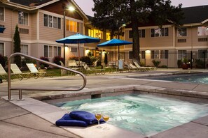 Un espace piscine d’hôtel avec des chaises longues, des parasols et un jacuzzi.