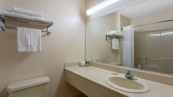 A bathroom with a toilet, sink, mirror, and towel rack.