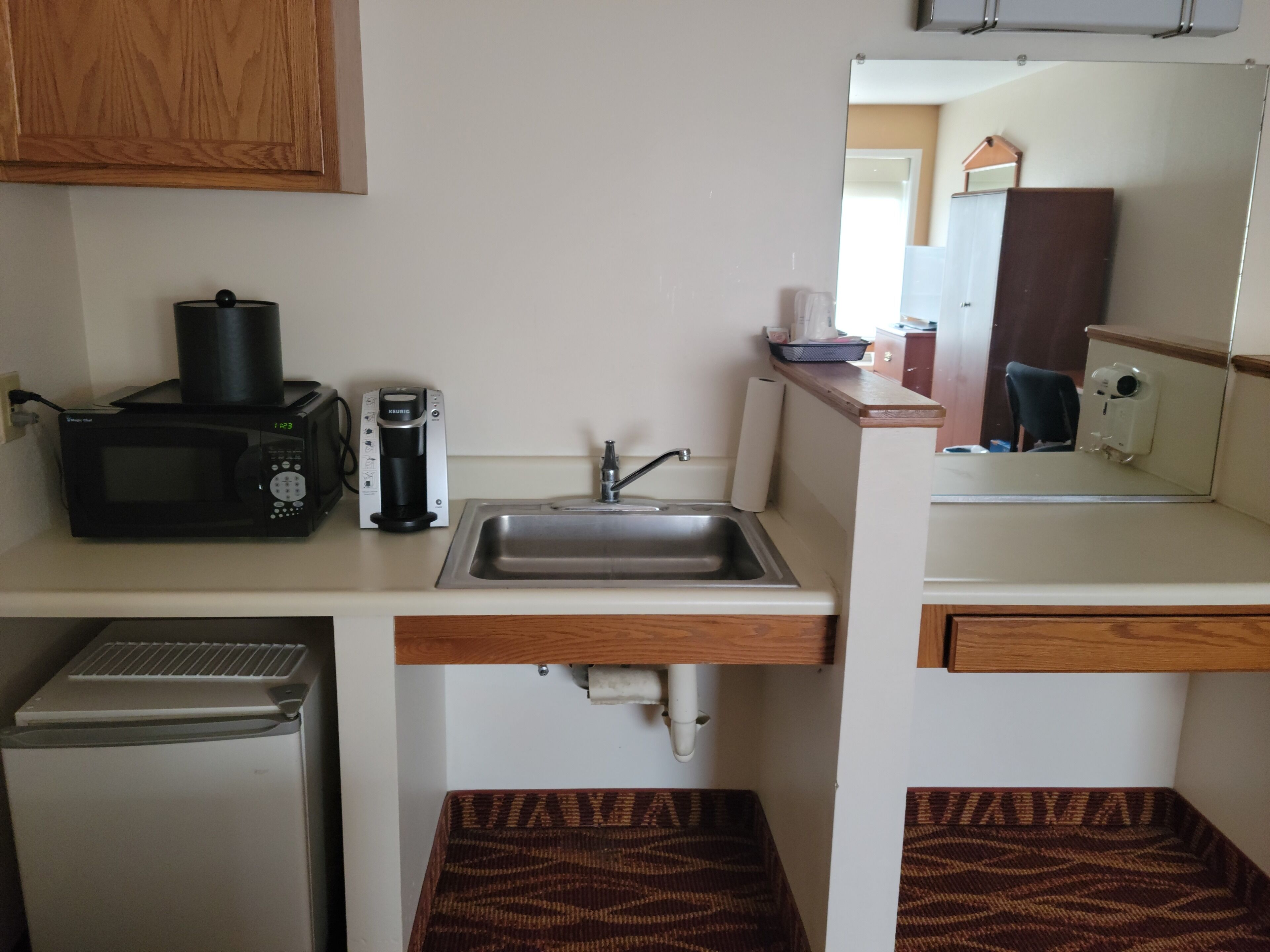 Cocina compacta con microondas, cafetera, lavabo y un refrigerador pequeño.