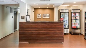 A reception area with a wooden reception desk, a wall-mounted sign for 'Sleep Inns & Suites', and a refrigerator stocked with beverages. - MainStay Suites Pittsburgh Airport (Pittsburgh)
