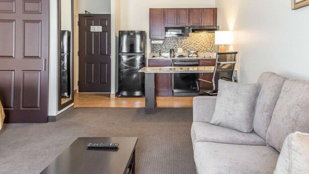 A compact living space with a kitchenette, a sofa, a coffee table, and a door. - MainStay Suites Pittsburgh Airport (Pittsburgh)