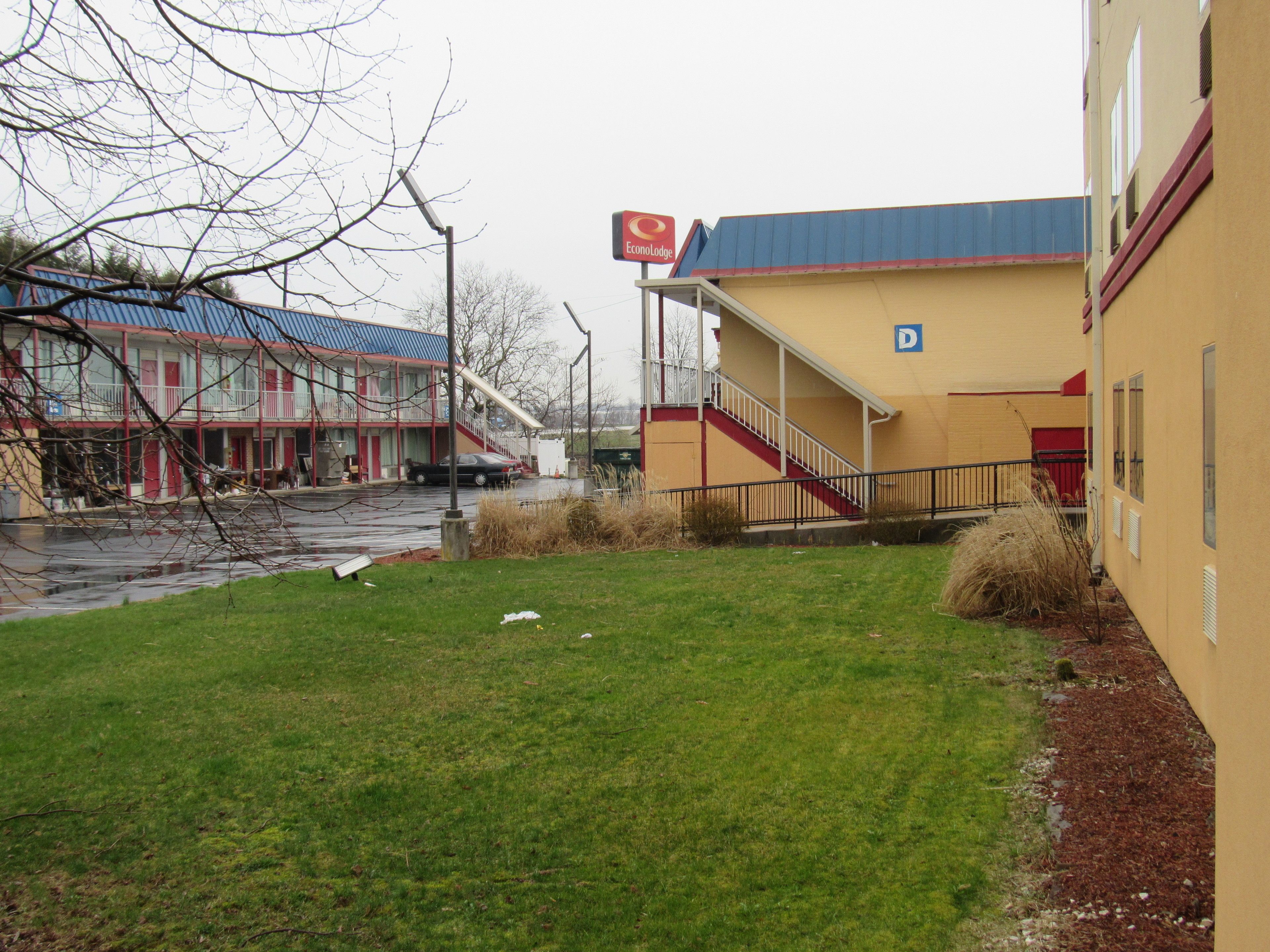 Un bâtiment à la façade rouge et jaune, avec une entrée bien visible et un espace de stationnement signalé par un panneau en forme de « D ».