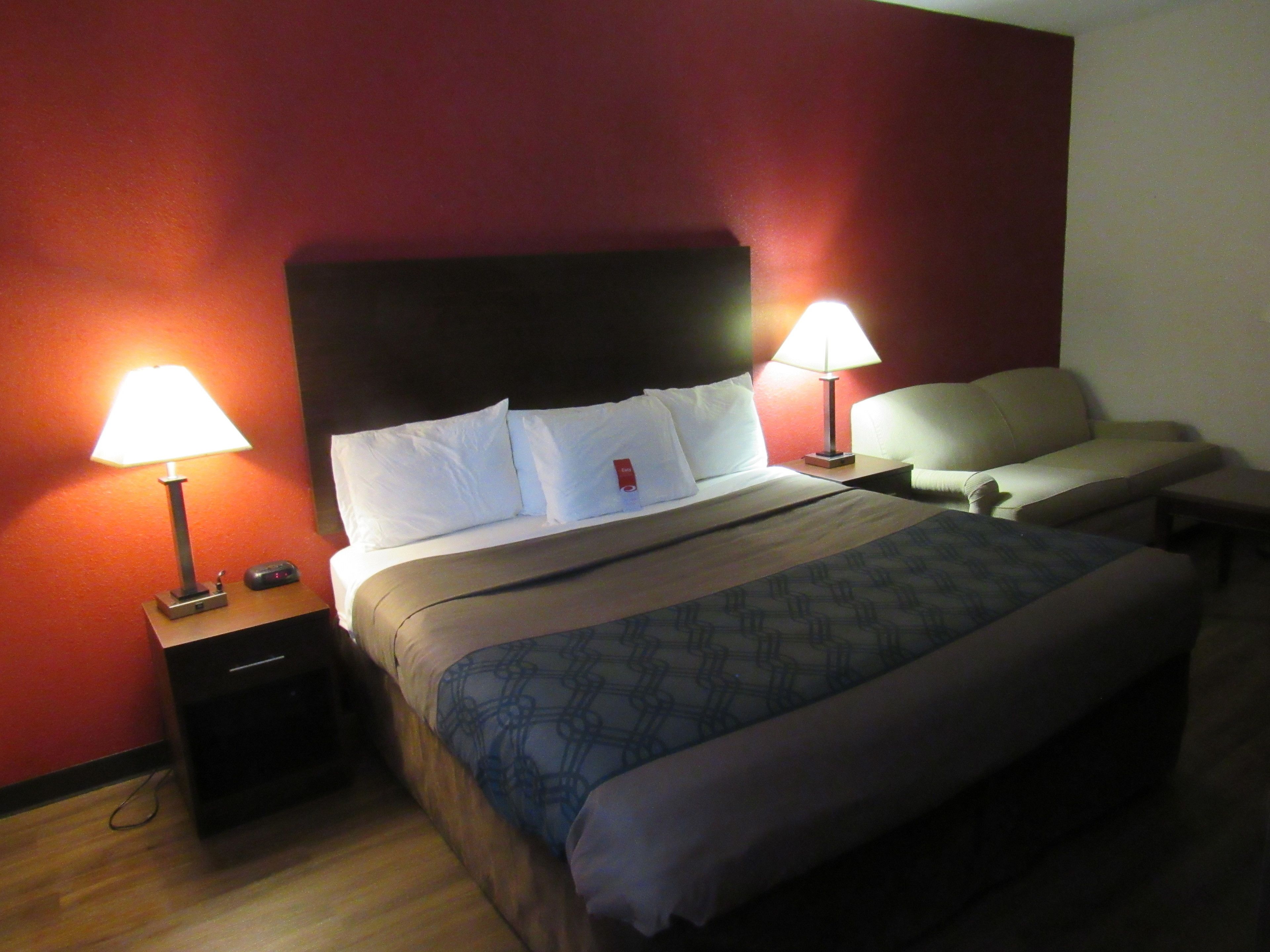 A hotel room with a bed, two bedside tables, a nightstand, a desk, and a chair.