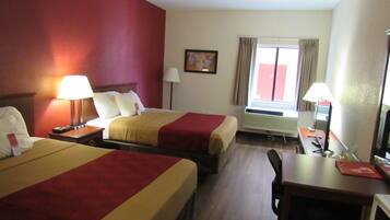 A hotel room with two beds, a desk with a computer, a chair, and a TV.