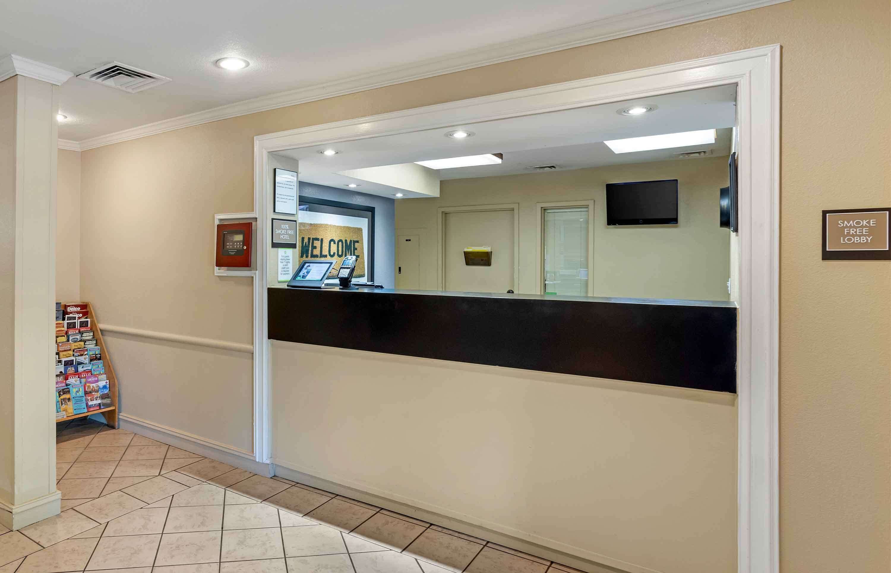 A reception area with a black reception desk, a welcome sign, a smoke-free lobby sign, and a small display stand with brochures.