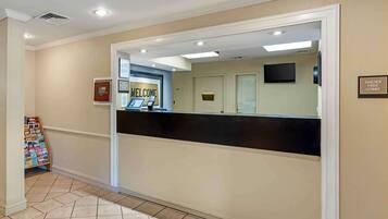 A reception area with a black reception desk, a welcome sign, a smoke-free lobby sign, and a small display stand with brochures.