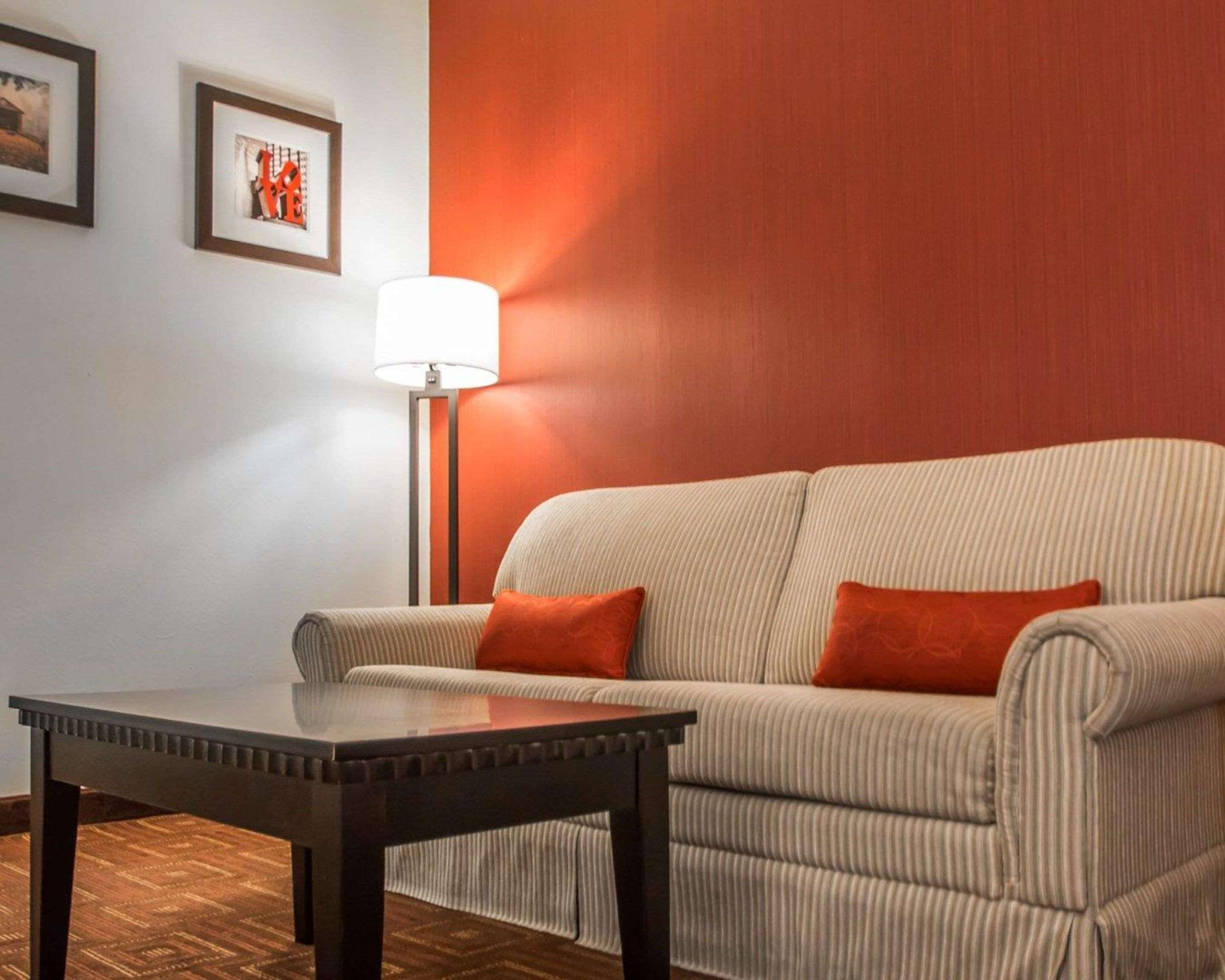 A room with a sofa, a table, and a lamp.