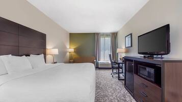 A hotel room with a large bed, a desk with a chair, a television, and a microwave.