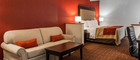 A hotel room with a sofa, a bed, a desk, and a chair.