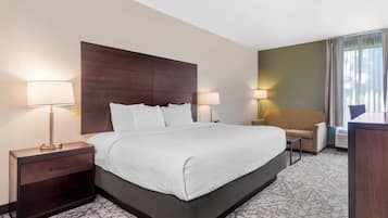 A hotel room with a large bed, two bedside tables with lamps, a sofa, and a desk.