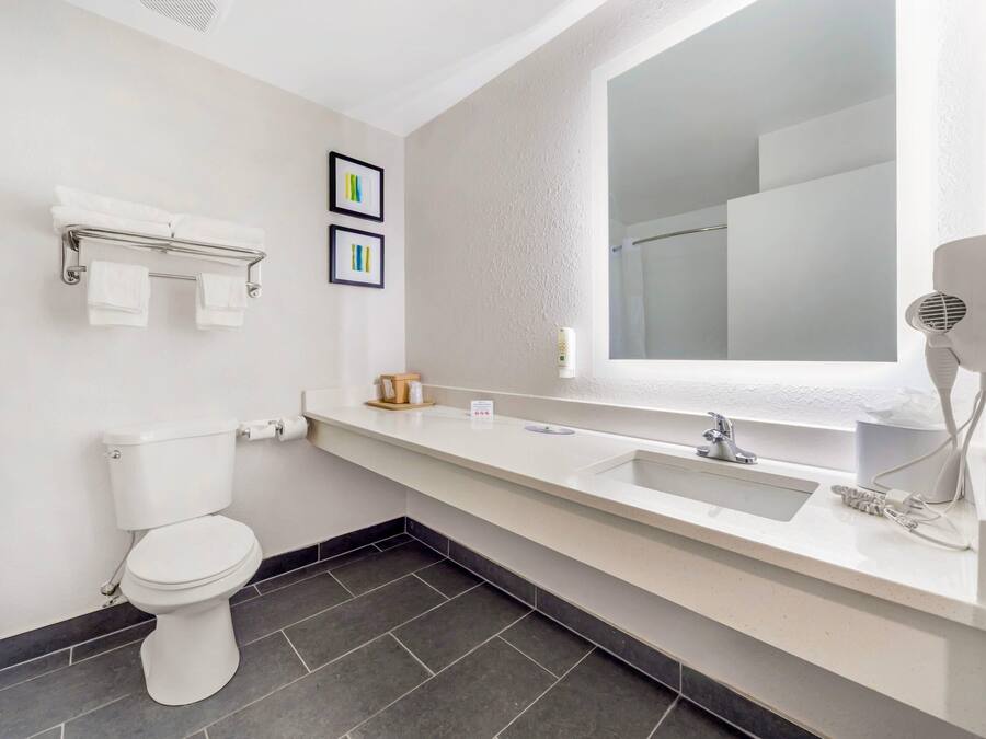 Un baño moderno con inodoro, lavamanos y un espejo grande.