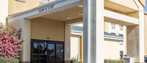 A hotel entrance with a covered walkway, a clear sign indicating guest parking, and a building number 1901.