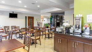 Um restaurante com mesas e cadeiras de madeira, um balcão com uma máquina de café e uma televisão na parede.