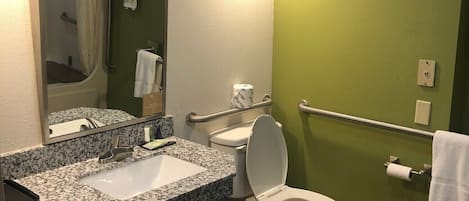 Ein Badezimmer mit Marmorwaschtisch, Toilette in Weiß, Spiegel und grüner Wand.